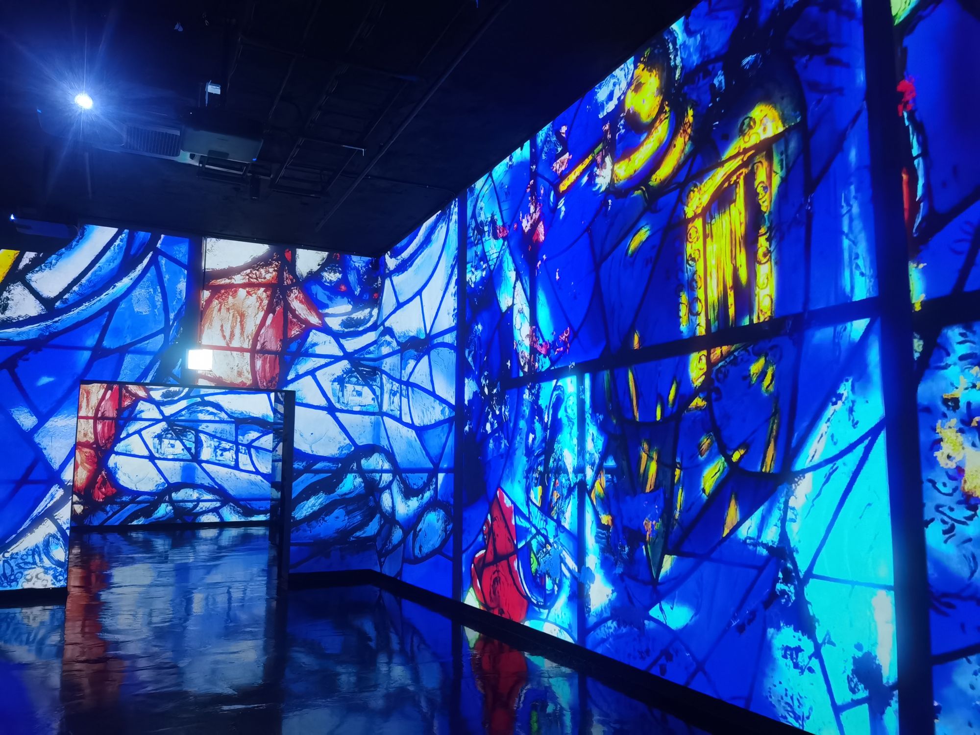 Chagalls Glasfenster als Projektion über Wände und Boden des Saals