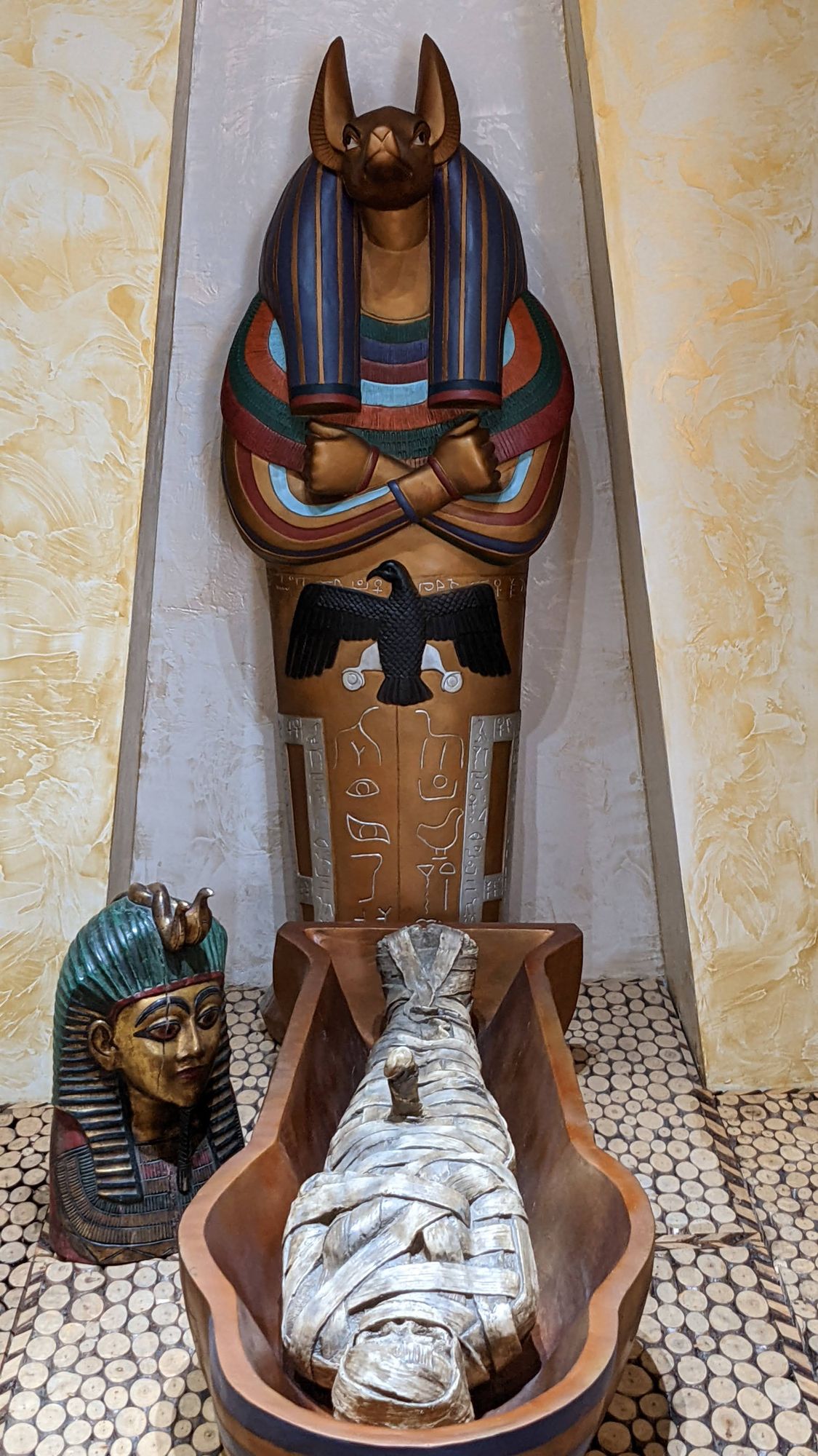 A sarcophagus with the head of Anubis, a bandaged mummy and a pharaoh's bust in front