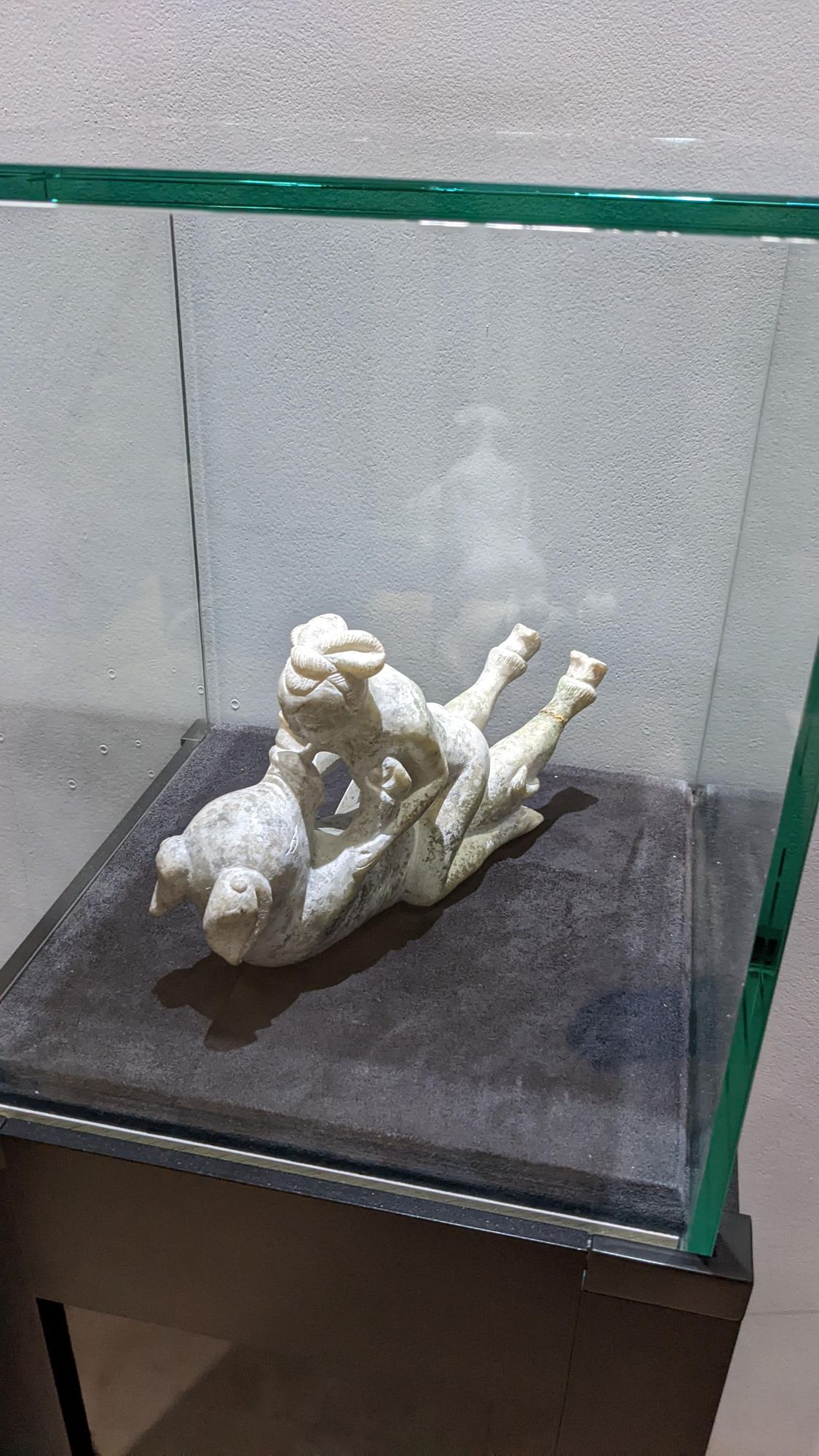 A small white figure group of a couple in a glass case