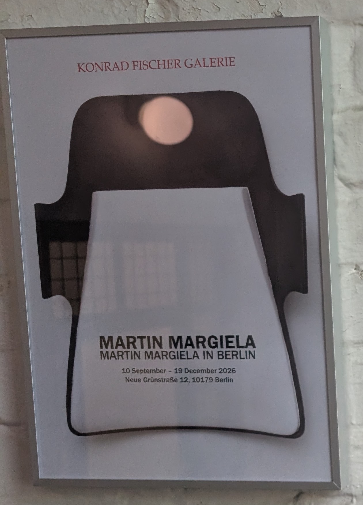 Plakat zu Martin Margiela, „Martin Margiela in Berlin“, an einer gekalkten Ziegelwand der Konrad Fischer Galerie